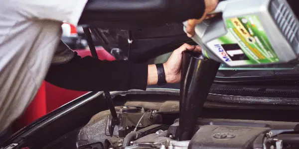 mechanic pouring oil into engine during car maintenance work